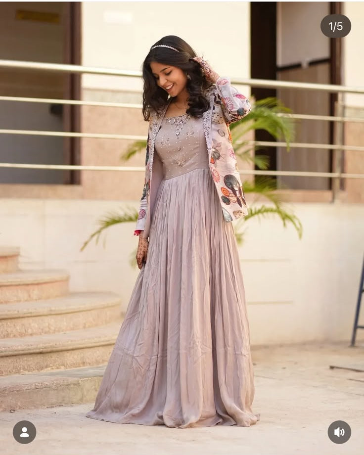 A woman modeling a long, floor-length lavender dress with a sheer embroidered overlay and floral sleeves, shown in an Instagram-style post. The dress has a dusty lavender-purple hue with intricate embroidery on the bodice and sleeves.